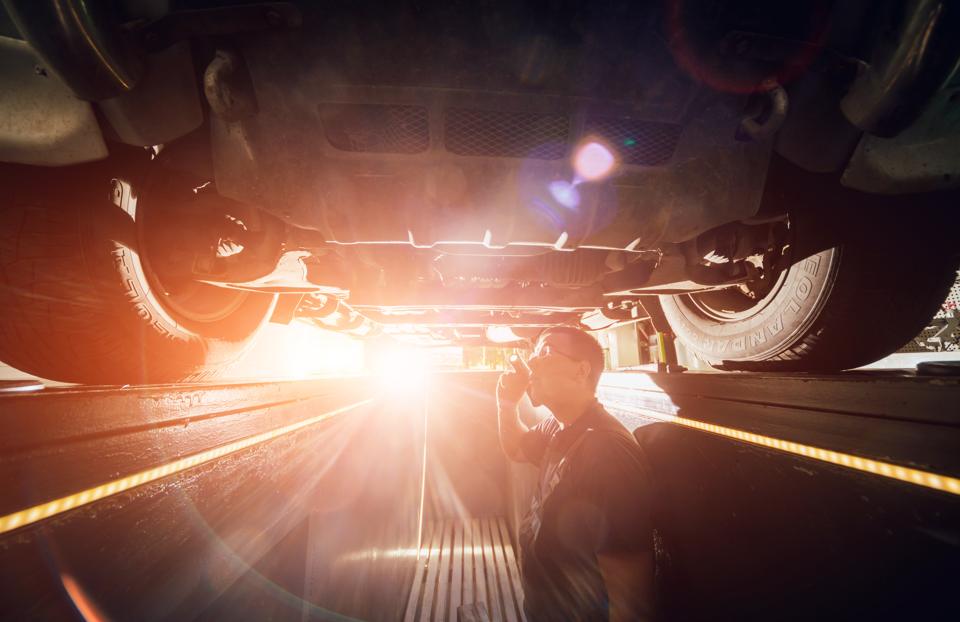 Car mechanic examining a lifted car