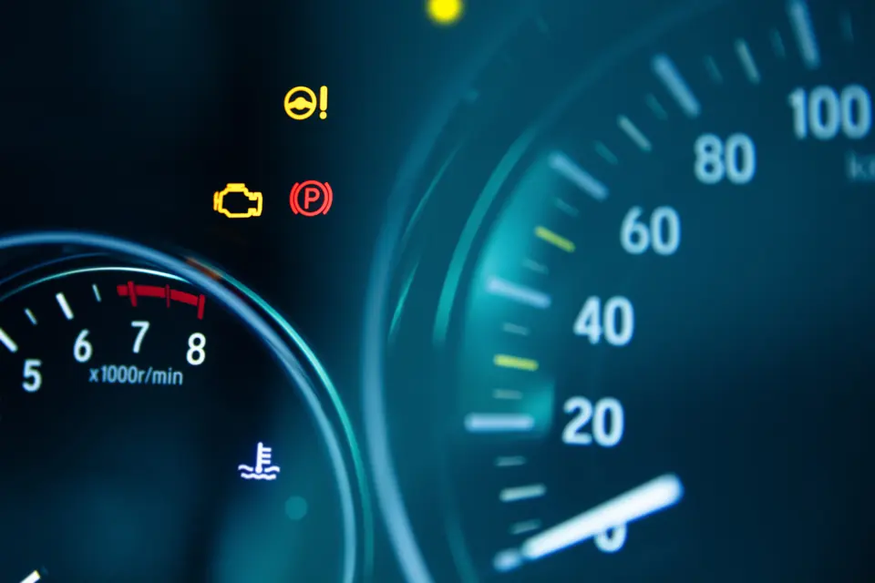 Warning lights lit on a car dashboard beside the speedometer