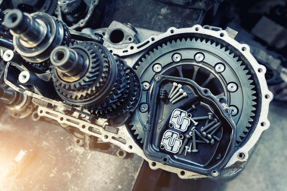 A disassembled automatic transmission on a workbench, gears and clutch drum exposed