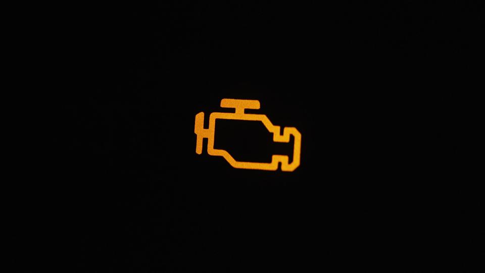 An amber check-engine light on a black background