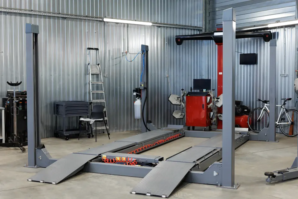 An empty service bay with a drive-on lift and alignment equipment